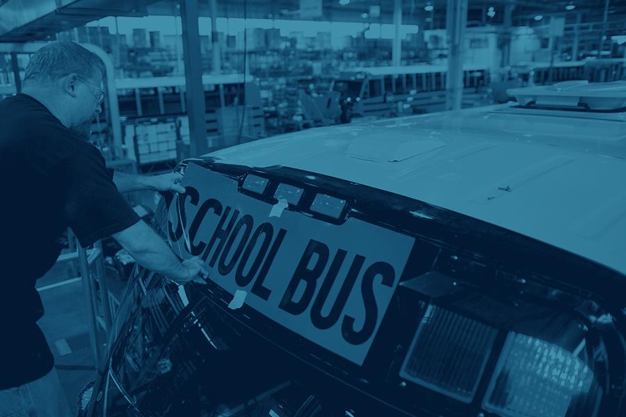 Worker in factory working on school bus