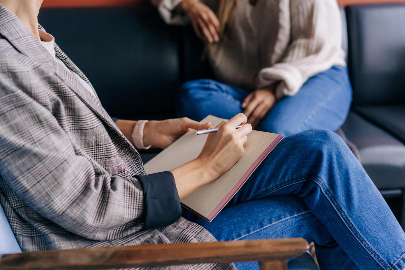 Close-up of a psychologist's hands writing down notes about a patient in a notebook. The psychologist makes a social survey of the reference group. A professional is talking to a client