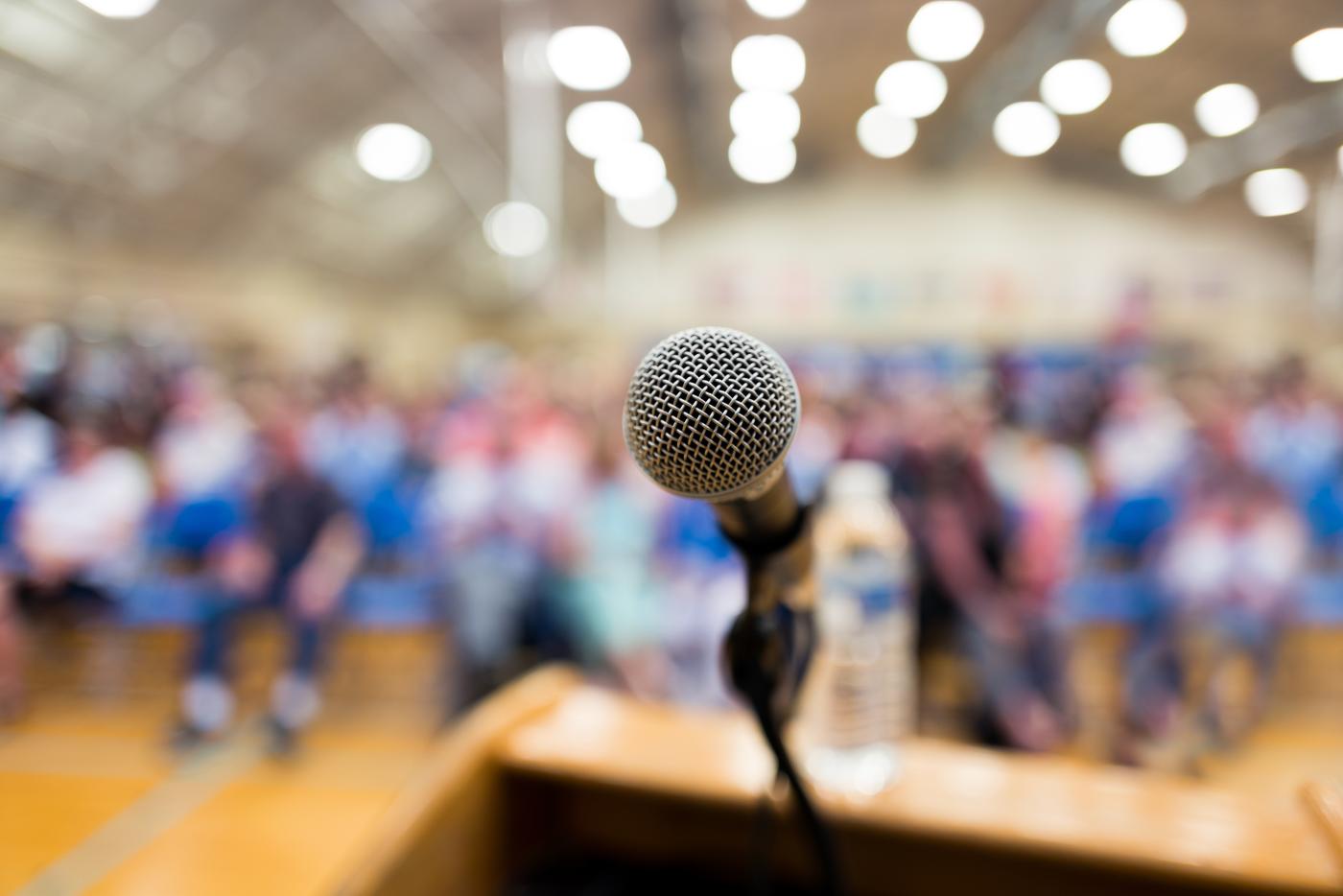 A microphone on stage in front of a crowd.