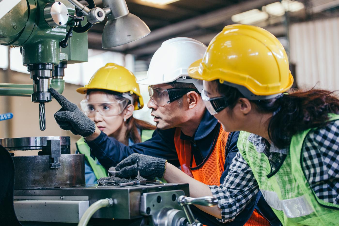  manager showing case study of factory machine to two engineer trainee in protective uniform. teamwork people training and working in industrial manufacturing business