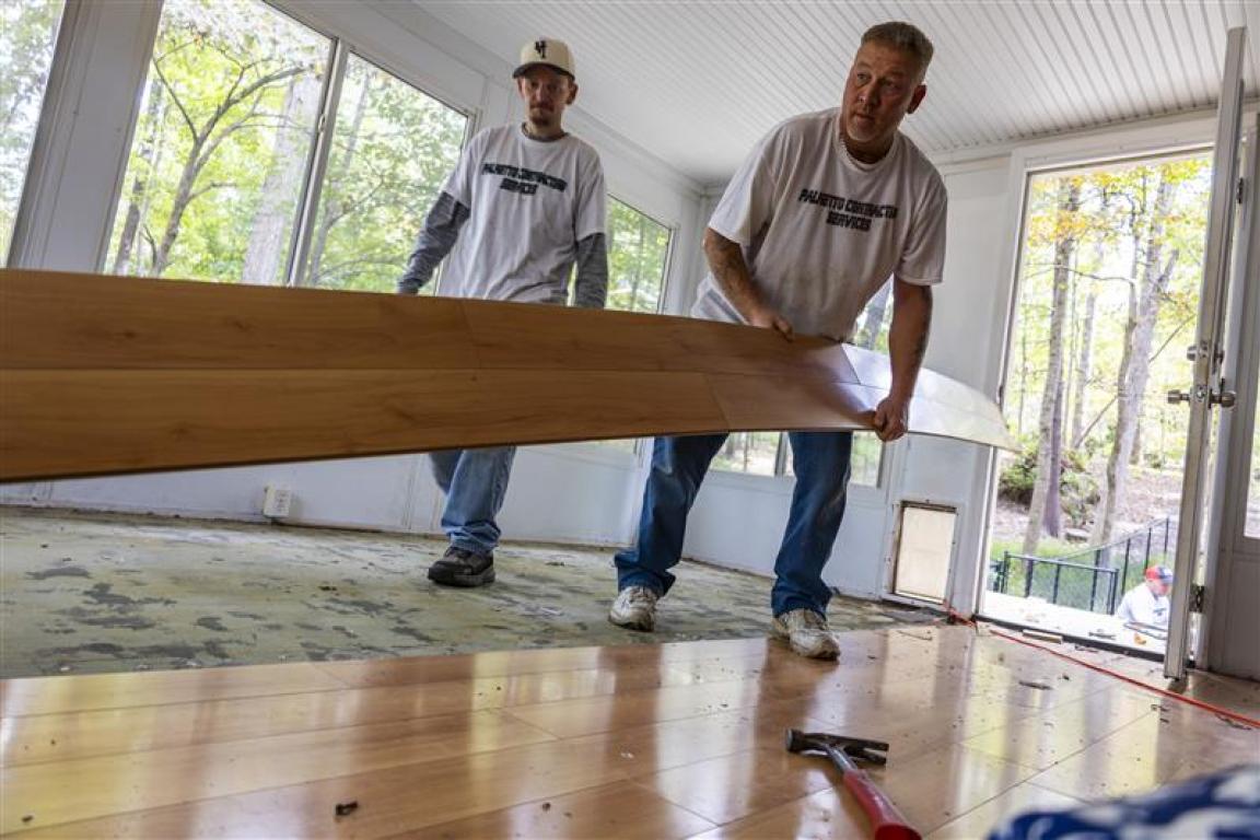 Construction crew replacing flooring in a home with water damage from Hurricane Helene