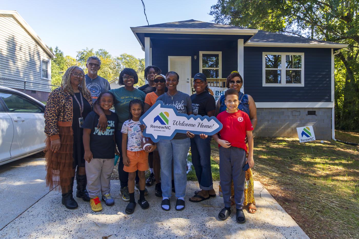 family holding real estate key in front of home
