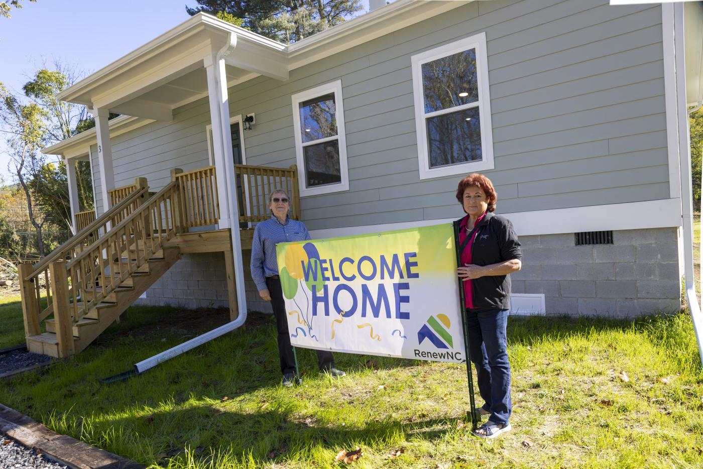 parents standing in front of home with renew nc banner