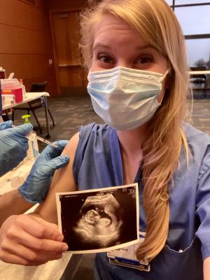 A portrait of Paige Cisa, MD, holding an ultrasound photo while receiving a vaccine injection