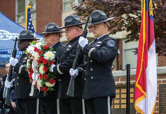 Four honor guard members in uniform laying a floral wreath