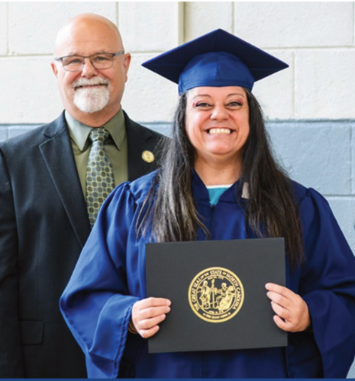Graduate in cap and gown holding a diploma