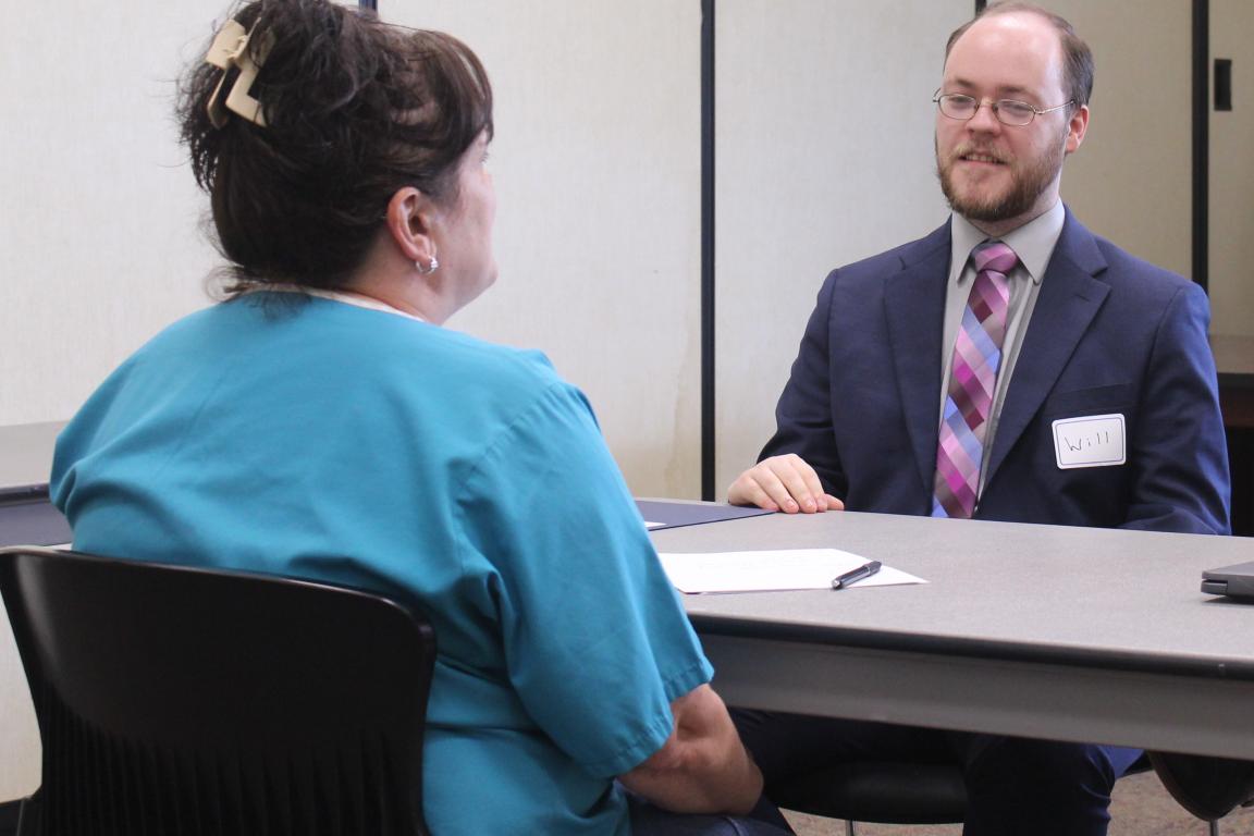 Male student speaks with WCCW woman in teal shirt.