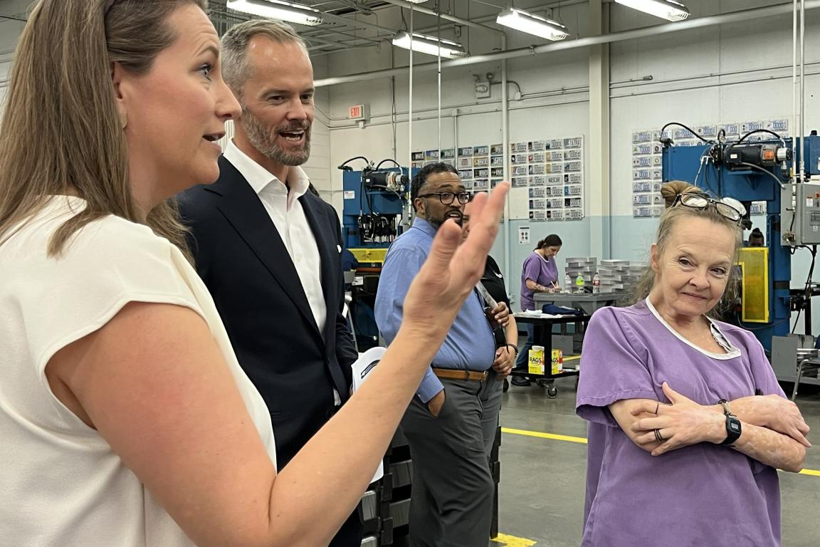 Sec. Leslie Dismukes in a dress speaks with N.C. Commerce Sec. Lee Lilley in a blue suit and a justice-involved lady in purple.