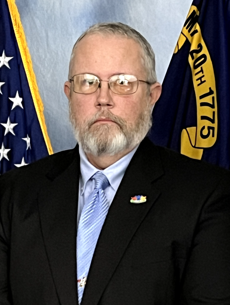Robert Norvel in front of US and NC flags