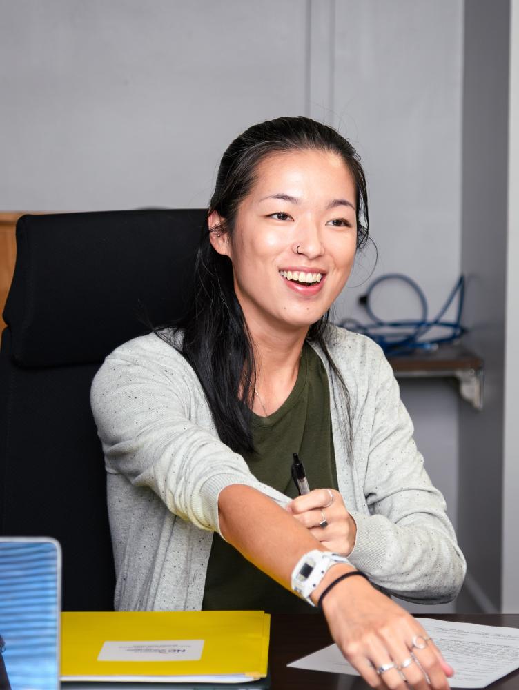 Young woman at table smiling and reaching for document