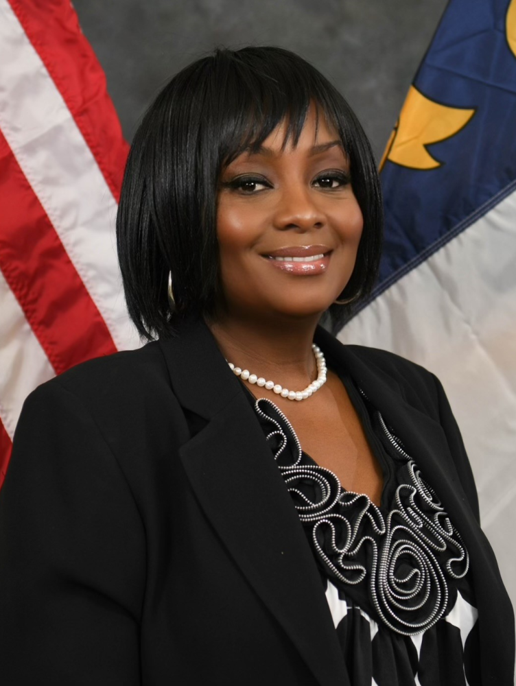 black woman in suit in front of flag