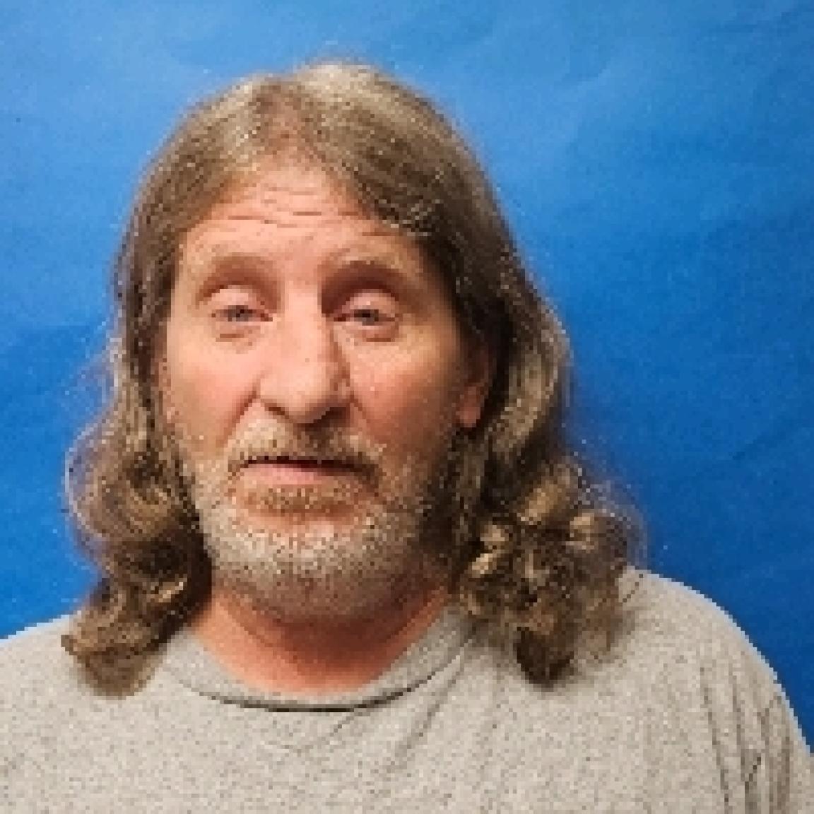 senior man with long greyish brown wavy hair and grey beard and mustache