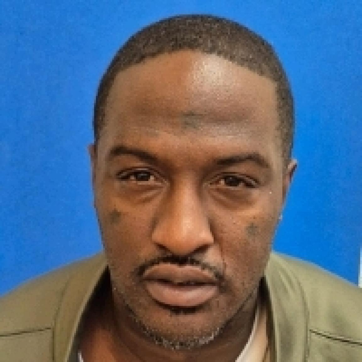 black man with thin mustache and short hair with khaki shirt