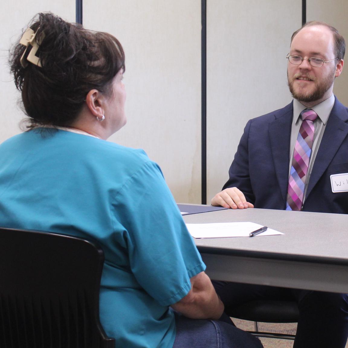 Male student speaks with WCCW woman in teal shirt.