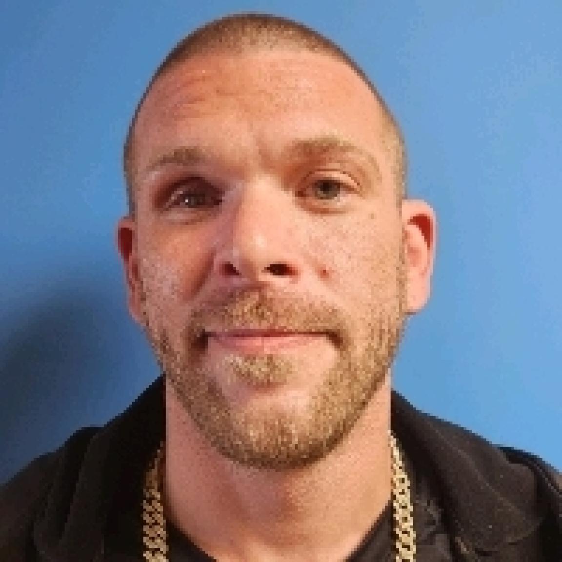 white man smiling with short cropped hair and full, cropped beard and mustache