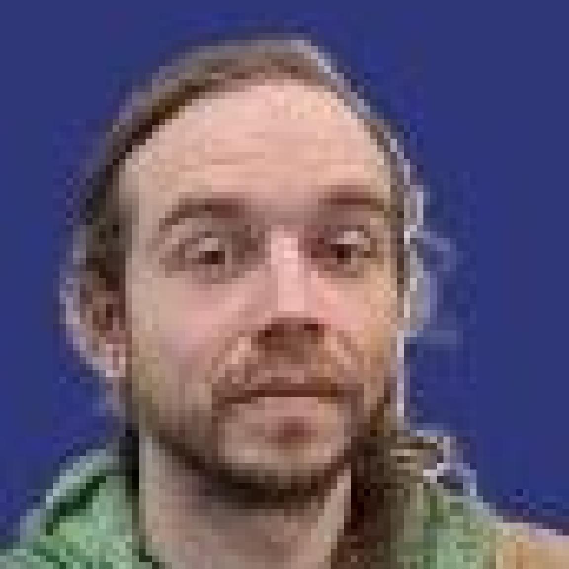 young white man with short beard and mustache in tan hoodie
