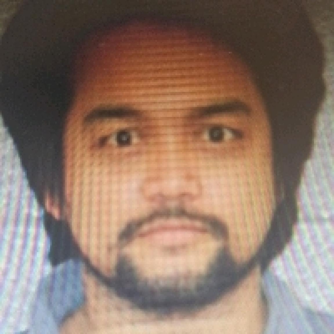 young Hispanic man with bushy hair and short cropped beard and mustache