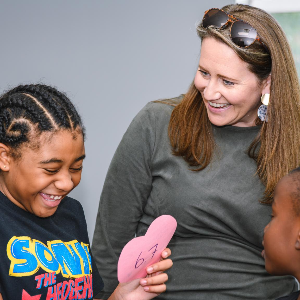 Woman laughs with child who is making a craft