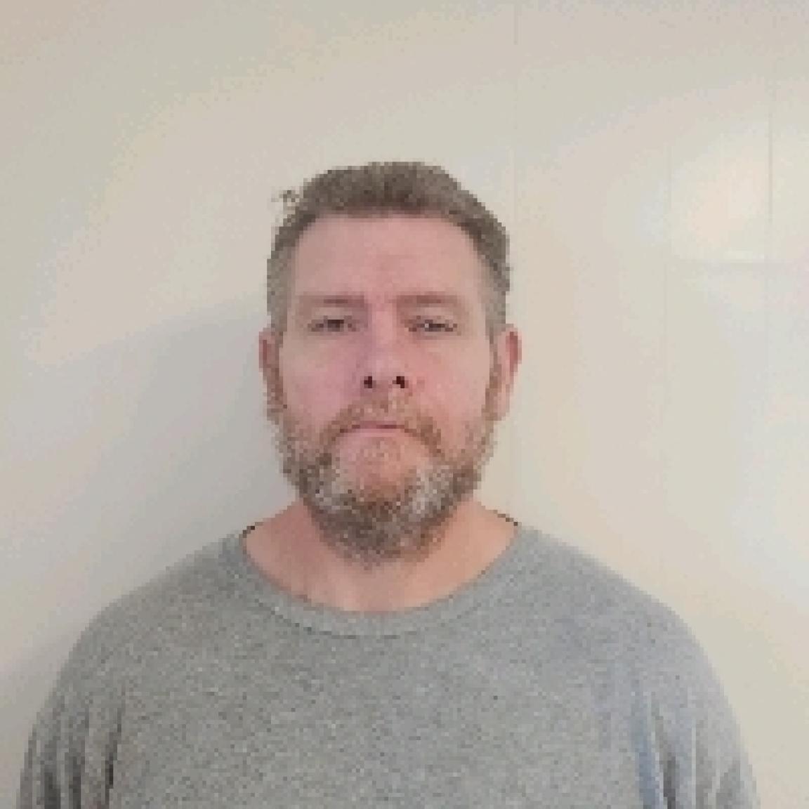 White man with brown hair and beard that is partly greying with mustache
