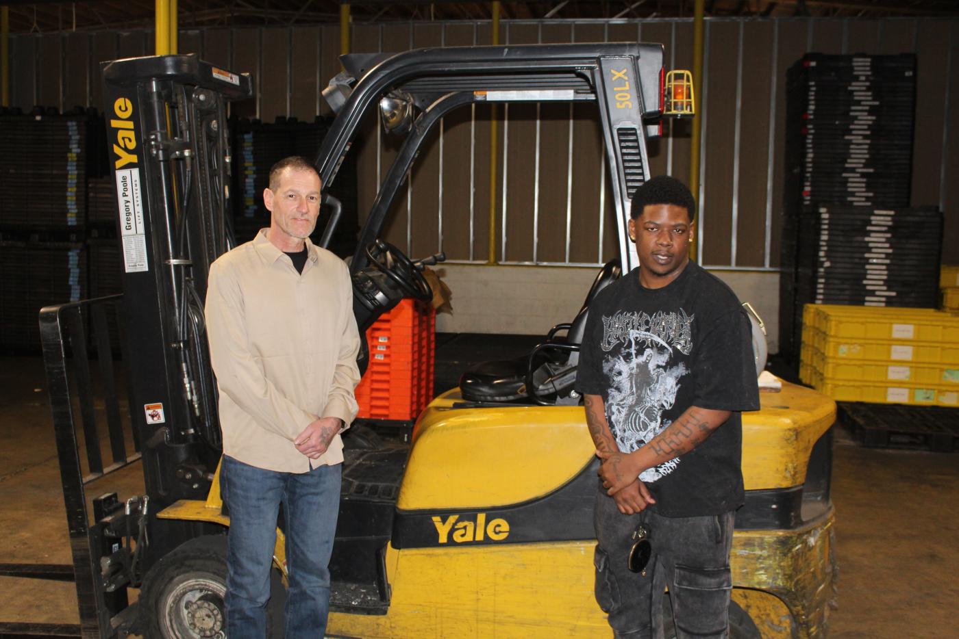 Two men standing next to a forklift in a warehouse