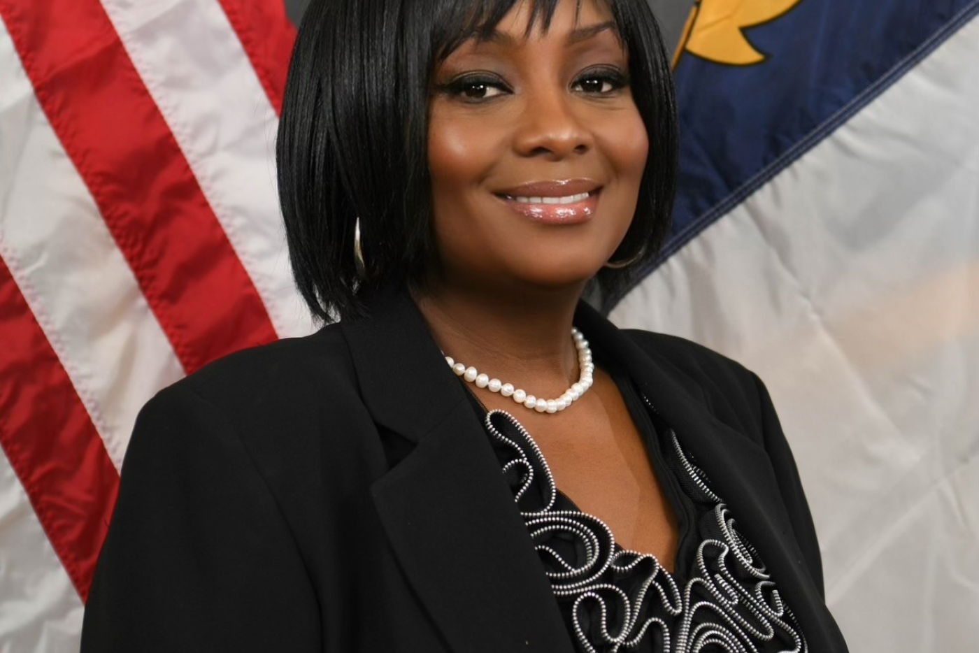 black woman in suit in front of flag