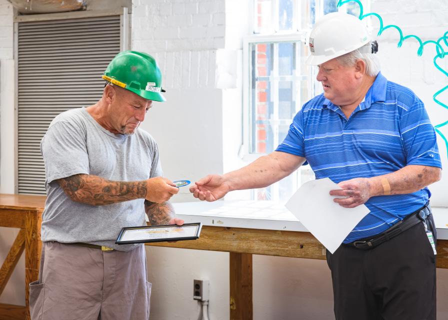 A person in custody receives his Electrical Journeyman Apprenticeship certificate during a ceremony
