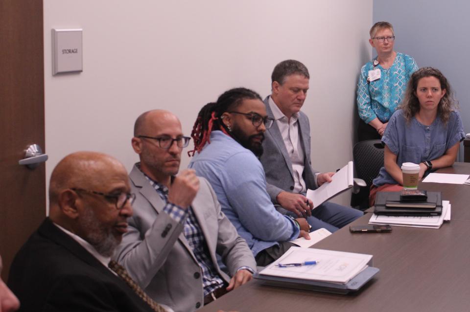 CPE male and female interns, with NCDAC personnel, sit at a table during a discussion.