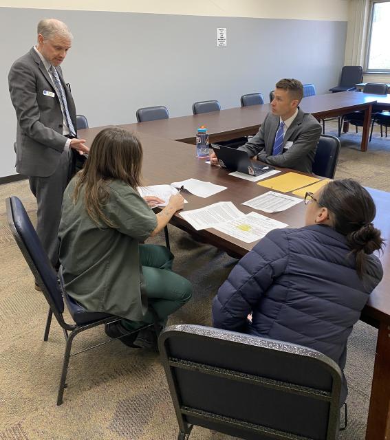 Two male lawyers and a female student speak with a WCCW justice involved person.