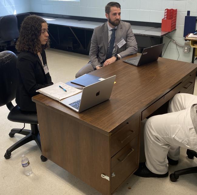 Male and female lawyers speaking with a Craggy CC person in custody.