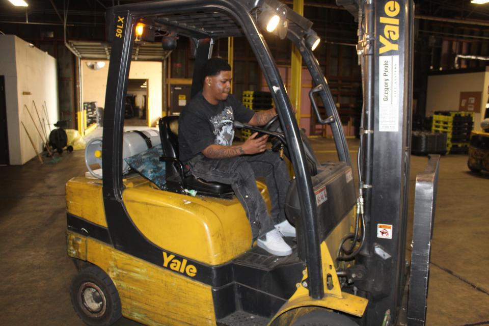 Arkeem Shields running a forklift in a warehouse