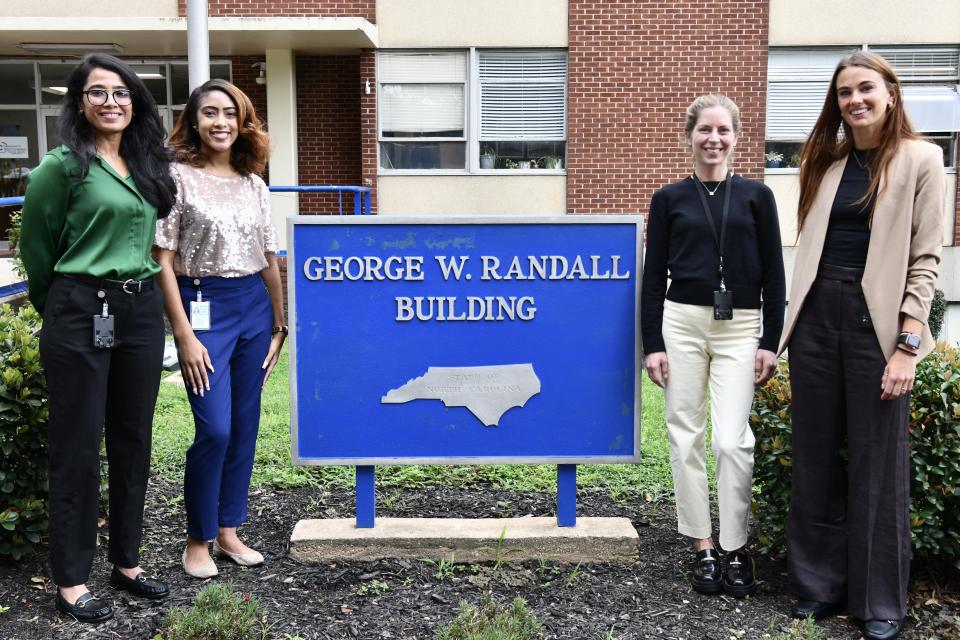 four women standing outside by NCDAC sign