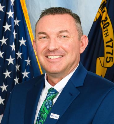 white man in blue blazer, white shirt, green tie