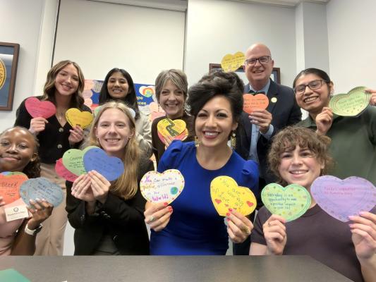 woman and kids hold up cut out hearts