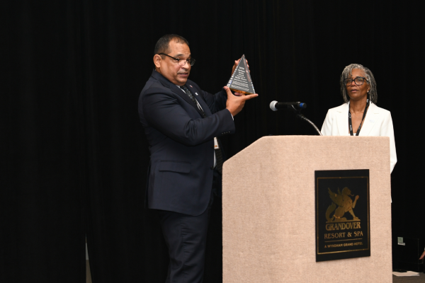 Man holds up award and woman looks on smiling