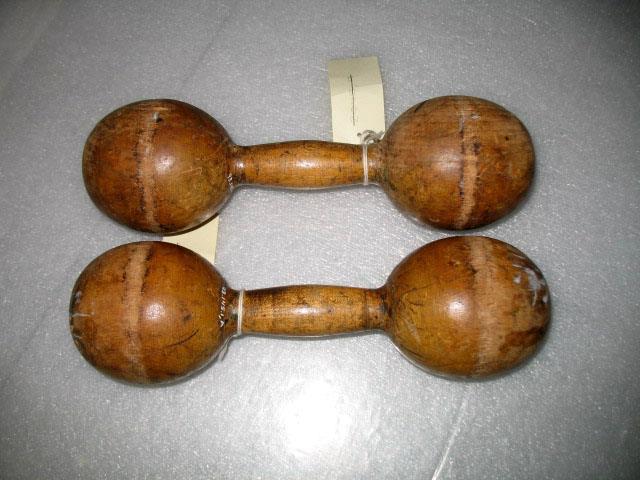 Pair of small, round wooden dumbbells with worn surfaces and attached paper tags.