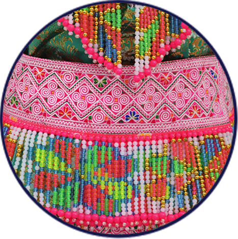 Circular artifact detail featuring vibrant Hmong embroidery and beadwork, including a pink fabric band with geometric stitching and colorful beaded fringe.