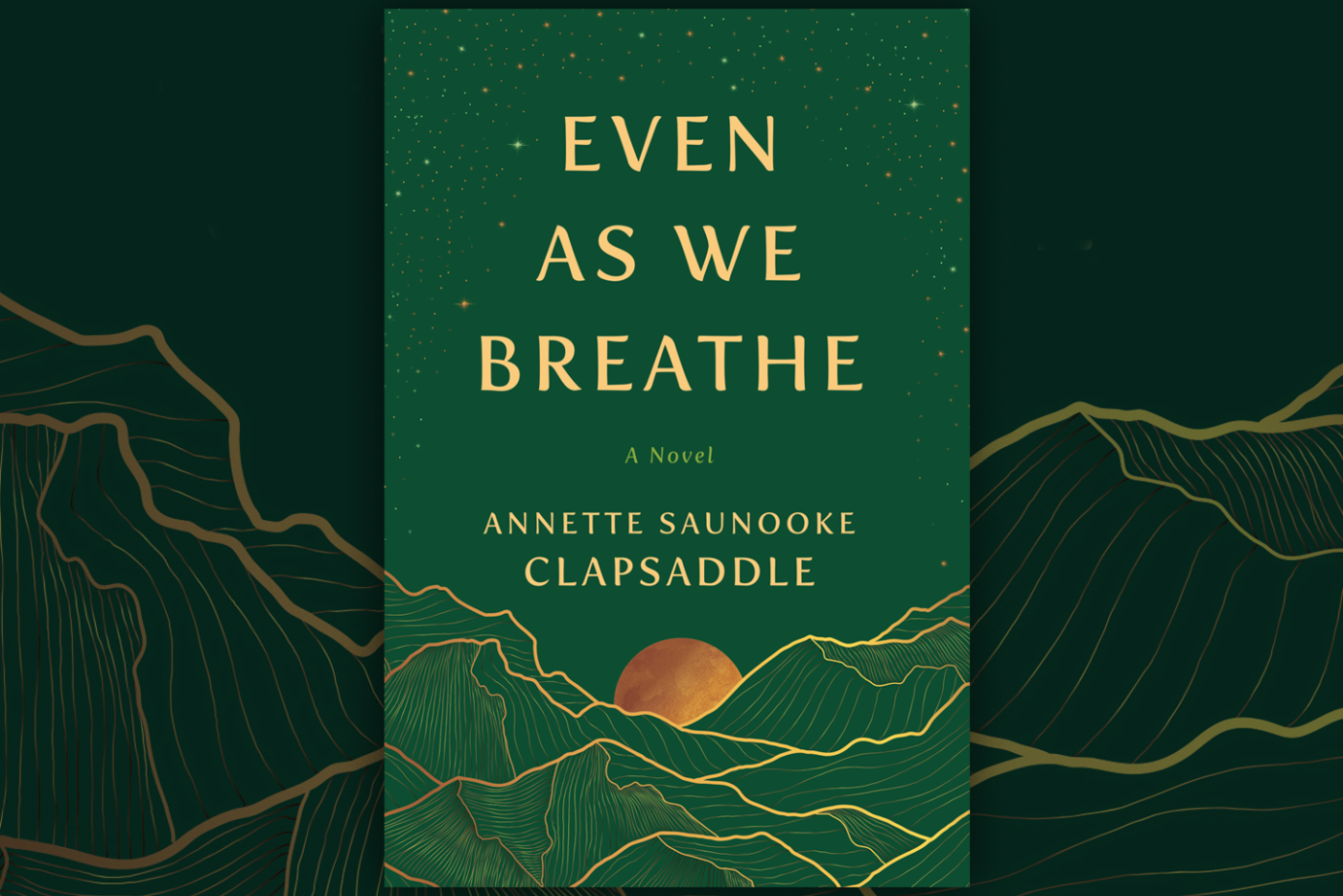 Book cover of "Even As We Breathe" by Annette Saunooke Clapsaddle. The design features a green background with gold illustrations of mountains and a sun, with starry details at the top.