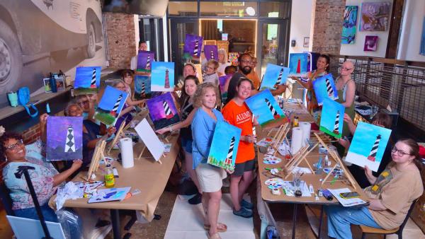 Artists at the Pop up event stand next to their artwork in a decorative hallway