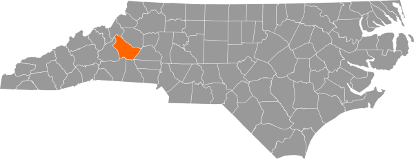 A gray map of North Carolina with Burke County filled in with orange.
