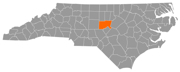 A gray map of North Carolina with Chatham County filled in with orange.