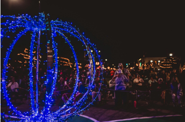 A blue, light-wrapped sphere frames a crowd gathered outdoors at night.