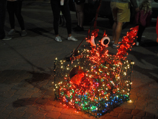 A crab-shaped decoration made of colorful lights sits on the ground at night.