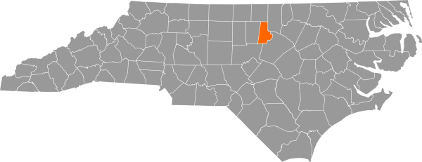 A gray map of North Carolina with Durham County filled in with orange.