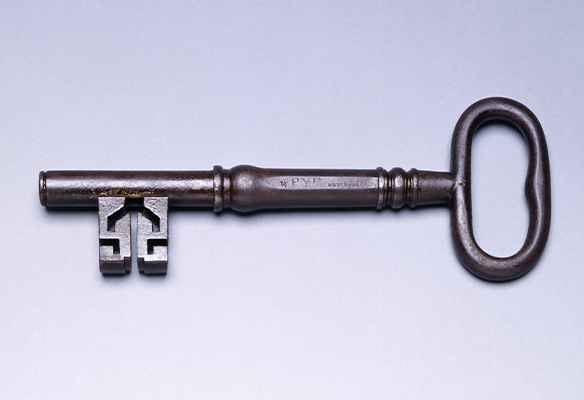 An antique metal key lying horizontally against a light background.