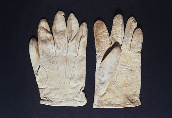 Two white deerskin gloves, one facing upwards and one facing downward, on a black background.