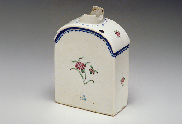 A white tea caddie with a floral design, blue accents, and a chipped lid.