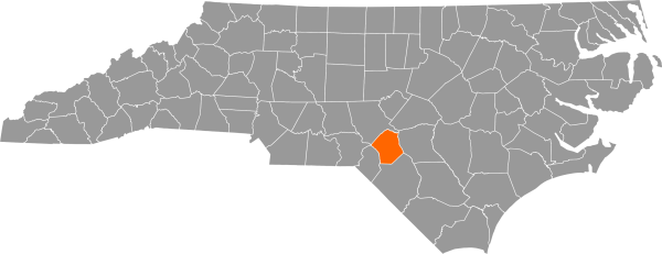 A gray map of North Carolina with Hoke County filled in with orange.
