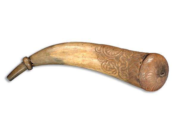 A tan horn with carved decorative patterns and a capped end.