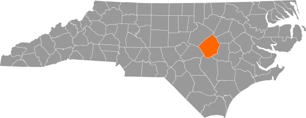 A gray map of North Carolina with Johnston County filled in with orange.