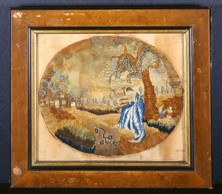 Framed embroidery depicting a woman in a blue-and-white dress beneath a tree.